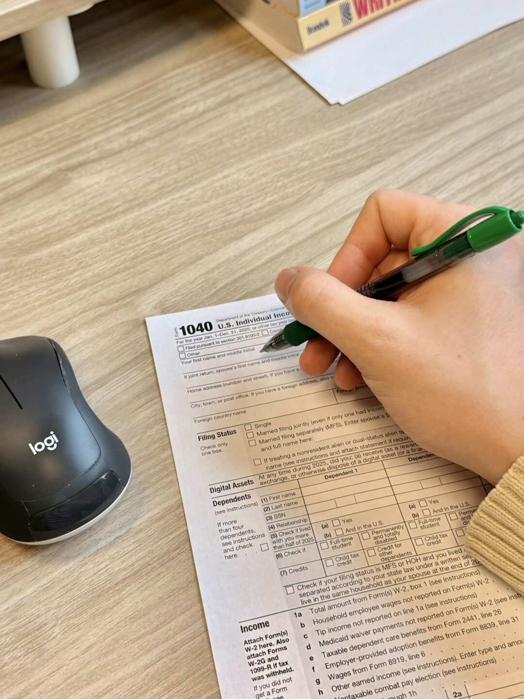 A hand completing an IRS Form 1040 beside a keyboard